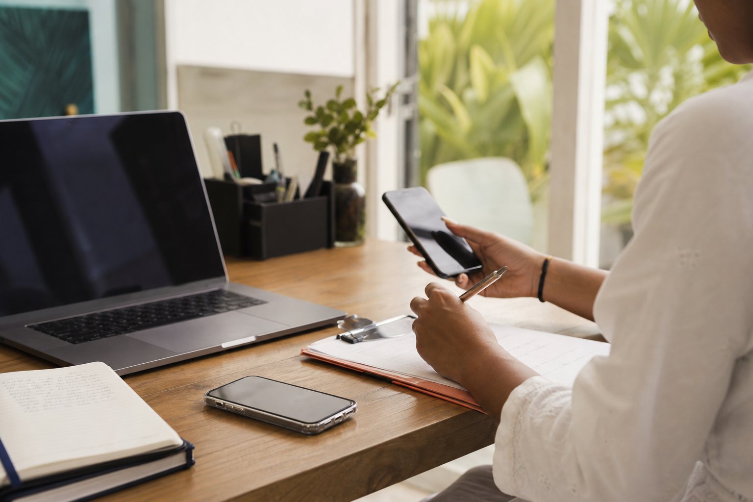 A service business operator working with a laptop, phone, and paper notes